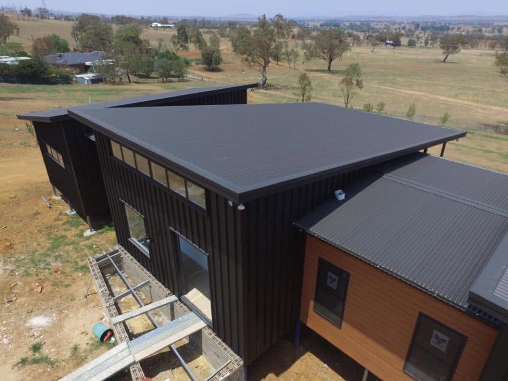 A newly finished dark metal roof on a rural home beside open paddocks