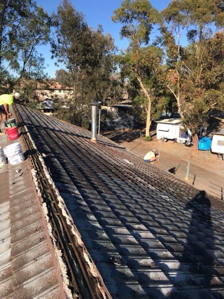An old tile roof being stripped back with new sheeting going on behind