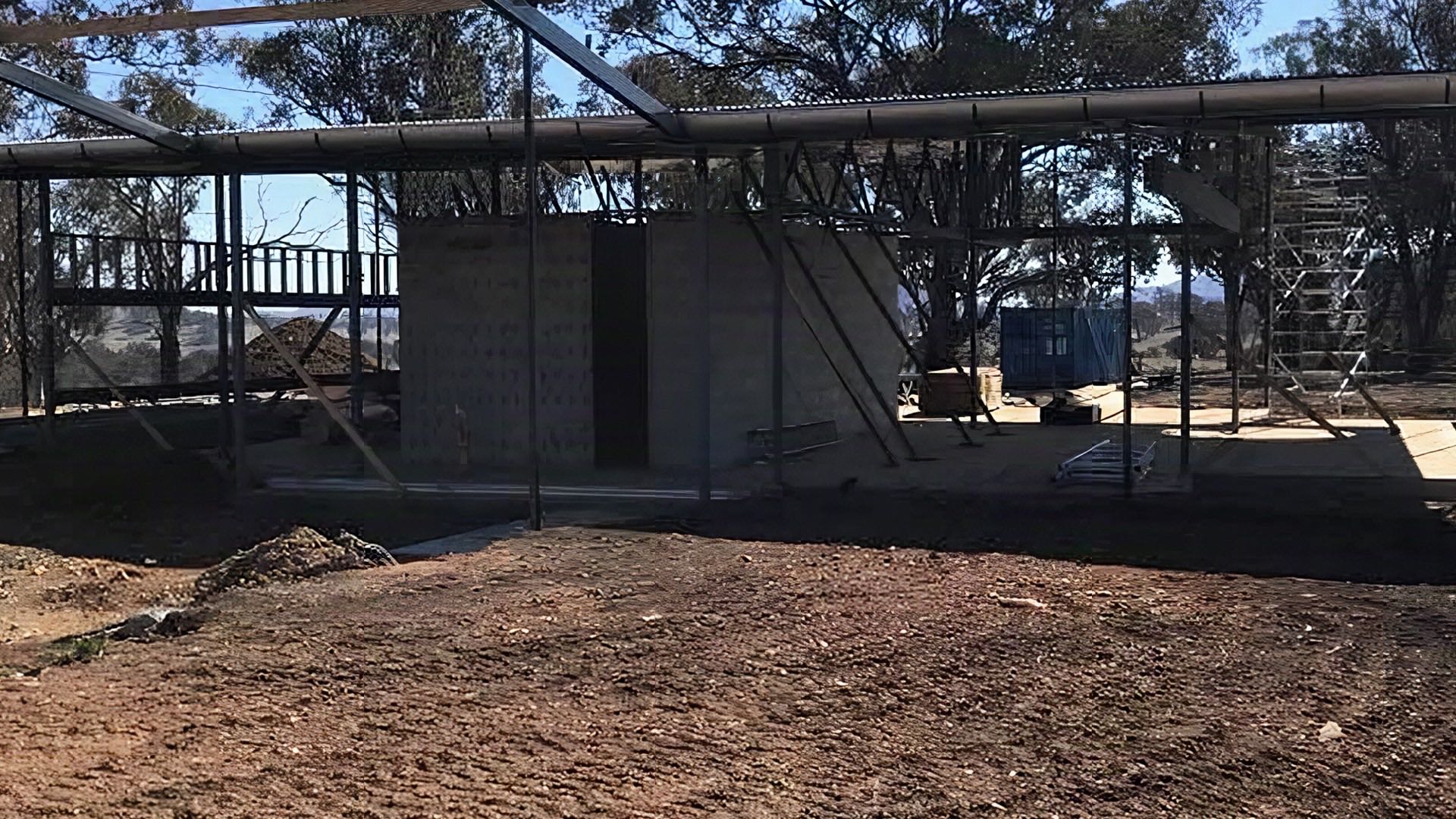 A steel roof frame going up on a rural block with hills behind
