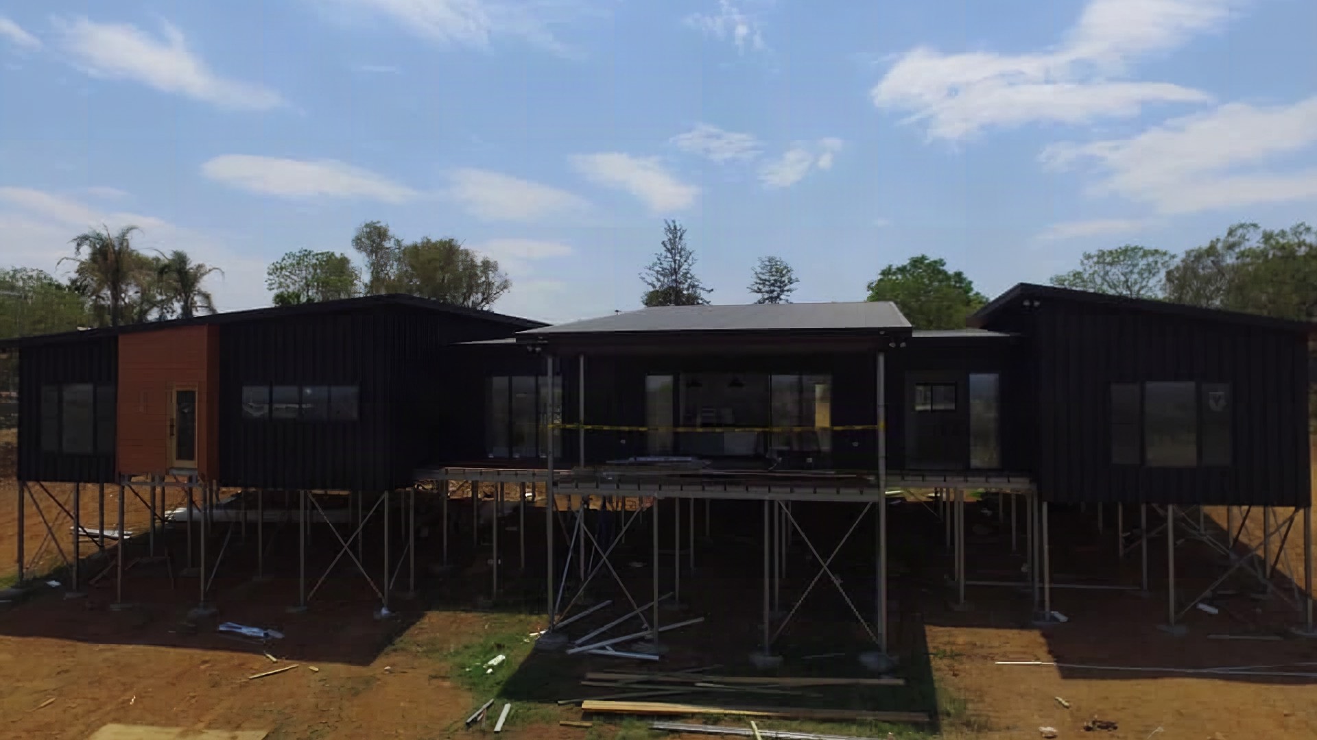 A dark steel roof on a new building set on red-brown ground