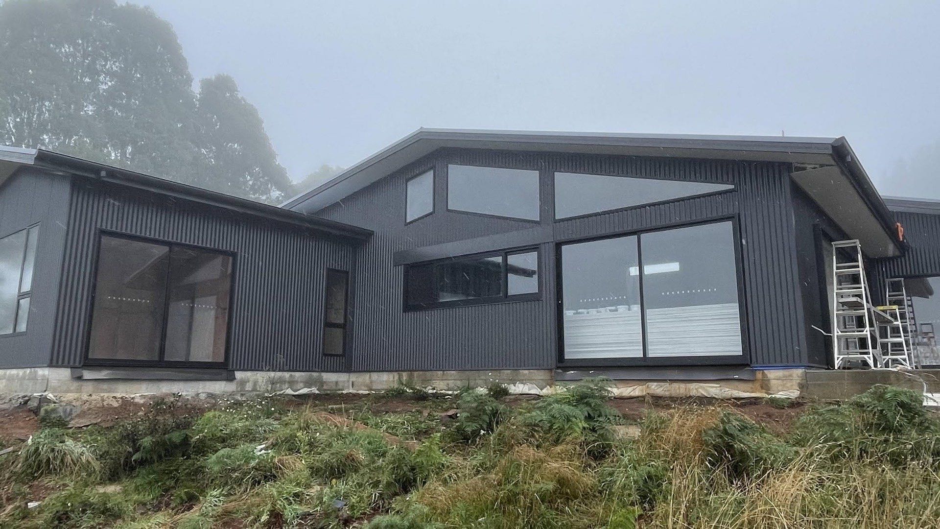 A home with a dark metal roof on a misty New England hillside