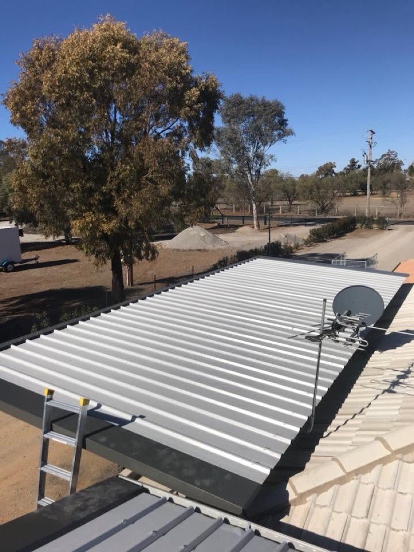 A large new steel roof on a rural shed with gum trees and dry ground around it