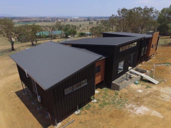 A finished dark metal roof on a rural home, seen from above