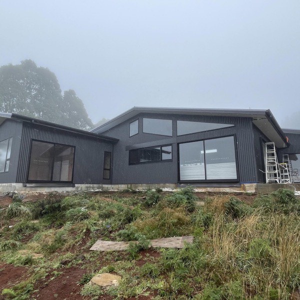 A home with a dark metal roof on a misty hillside