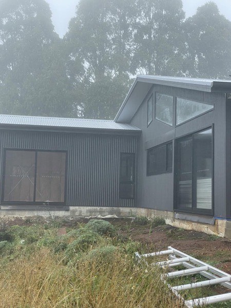 A grey steel roof on a house with a shed alongside it
