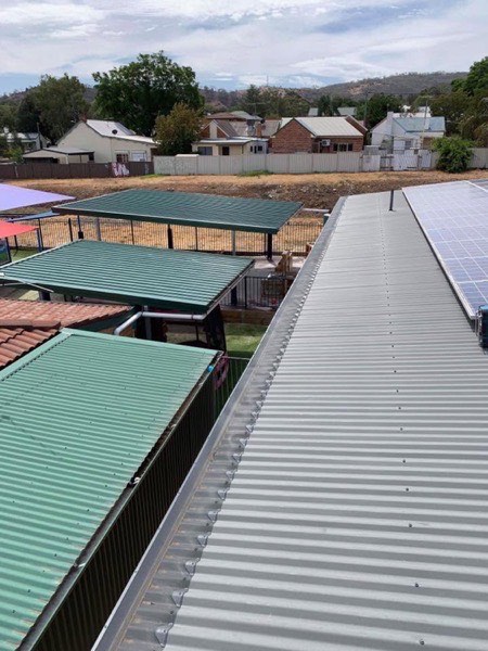 Green steel roofs on a row of sheds above a town