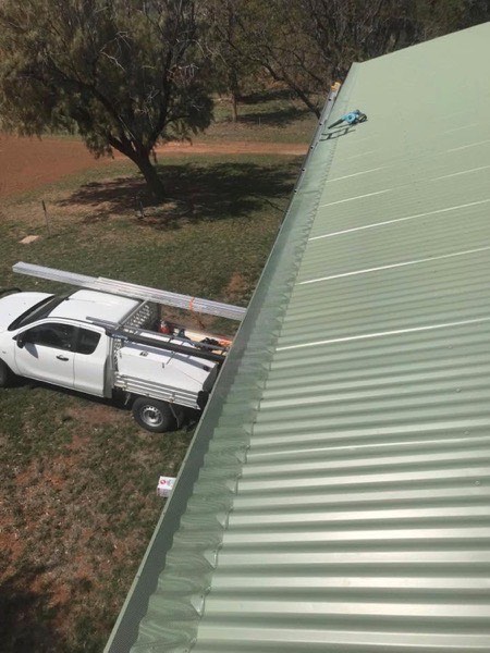 A green steel roof with a white work ute parked on the grass