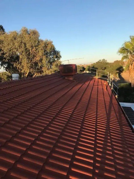 A red steel roof with open paddocks and trees in the distance