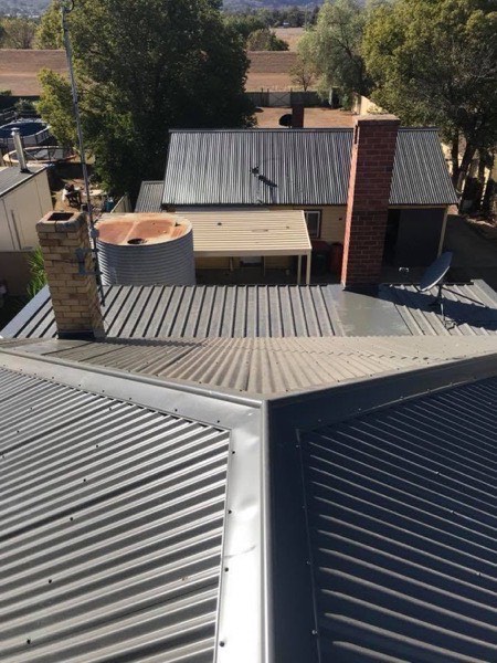 A dark steel roof running out over a pergola