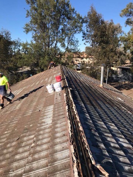 A roofer in hi-vis working along an old roof